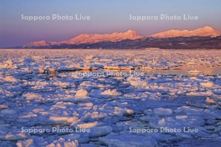 夕焼けのオホーツク海の流氷と知床連峰