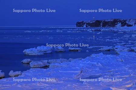 夜の流氷と能取岬の灯台の明かり