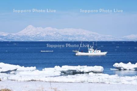 知床連山と流氷と漁船