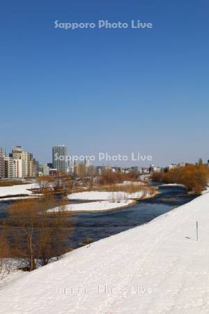 雪解けの豊平川とマンション群